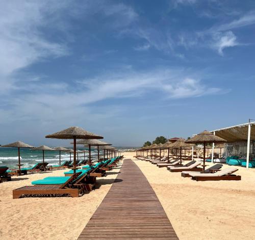 una fila de sillas y sombrillas en una playa en Sea View Villa in Agia Thekla, en Ayia Napa