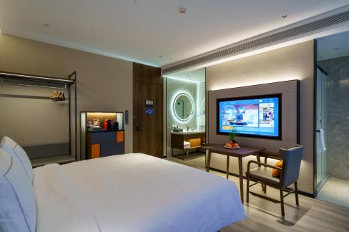 een slaapkamer met een groot bed en een televisie bij UrCove by HYATT Futian CBD in Shenzhen