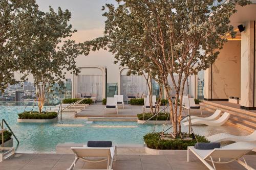 uma piscina com cadeiras e árvores num edifício em Eastin Grand Hotel Phayathai em Bangkok