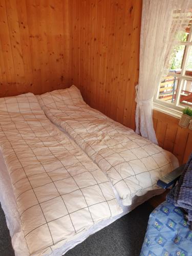 Ce lit se trouve dans une chambre en bois dotée d'une fenêtre. dans l'établissement Holiday Raustua Cabin, à Gol