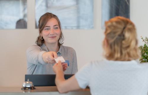 una mujer sentada en una mesa jugando un videojuego en Hotel Inn Design La Rochelle, en La Rochelle