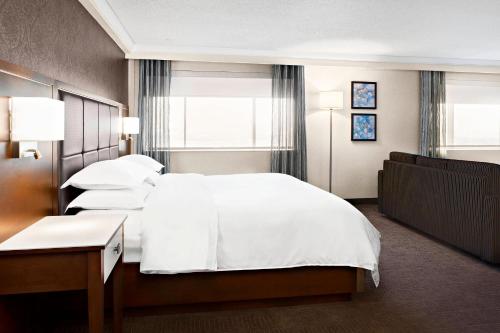 1 dormitorio con 1 cama grande con sábanas y almohadas blancas en Sheraton Laval Hotel en Laval