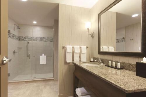 bagno con doccia, lavandino e specchio di Embassy Suites Saratoga Springs a Saratoga Springs