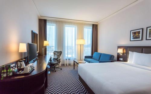 a hotel room with a bed and a desk and a television at Hilton Garden Inn Krakow Airport in Kraków