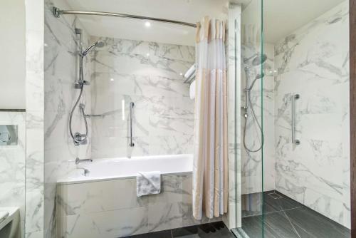 a bathroom with a shower and a tub and a sink at Hilton Garden Inn Krakow Airport in Kraków