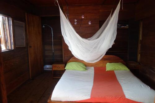 uma cama com uma rede pendurada num quarto em Robinson's Hut em Bure Town