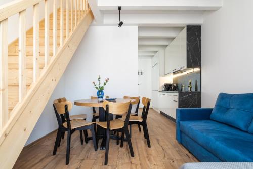 een woonkamer met een tafel en stoelen en een blauwe bank bij SOLEK Apartamenty i pokoje gościnne in Mielno