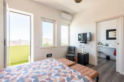 sypialnia z łóżkiem, telewizorem i oknami w obiekcie Eleventh Floor Suites w Cagliari