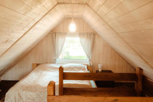 Bett in einem kleinen Zimmer mit Fenster in der Unterkunft Beneháti kunyhók in Matrafured