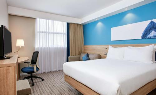 una camera d'albergo con letto, scrivania e TV di Hampton by Hilton Glasgow Central a Glasgow