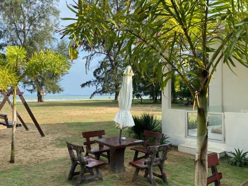 una mesa y sillas con una sombrilla y un árbol en DamaiiKu en Cherating