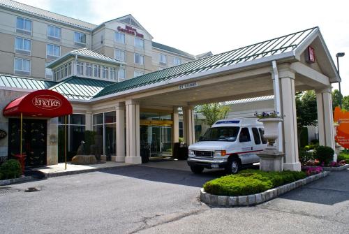 un furgone bianco parcheggiato di fronte a un edificio di Hilton Garden Inn New York/Staten Island a Staten Island