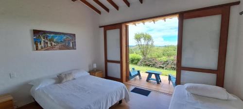 ein Schlafzimmer mit einem Bett und einem großen Fenster in der Unterkunft Finca Buena Vista in Guatapé