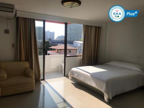 1 dormitorio con 1 cama, 1 silla y 1 ventana en Jomtien Longstay Hotel - SHA Plus Certified en Jomtien Beach