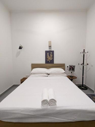 a bedroom with a large white bed with two slippers at Araam Inn in Nellaidhoo