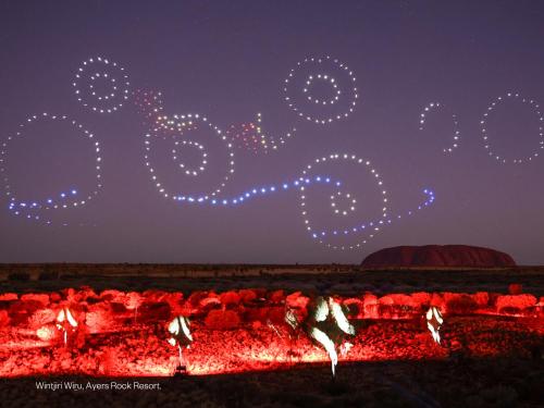 エアーズロックにあるエミュ ウォーク アパートメントの夜火の周りで踊る集団