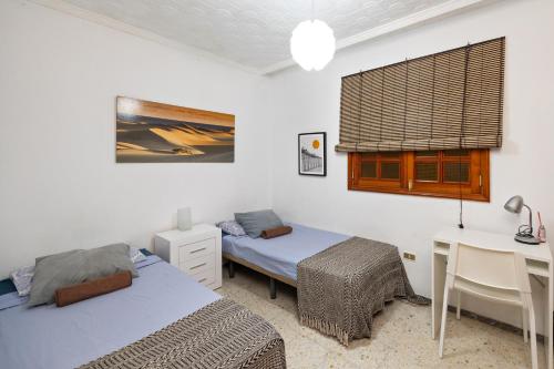 een slaapkamer met 2 bedden, een bureau en een tafel bij Kite & Surf Nomad House in Las Palmas de Gran Canaria