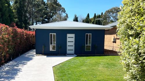 una casa blu con un prato davanti di Honey Fig Cottage, Bowral a Bowral