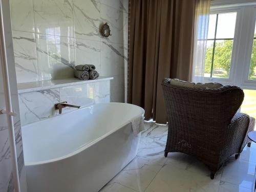 a white bath tub in a bathroom with a chair at Ombergs Golf Resort in Ödeshög