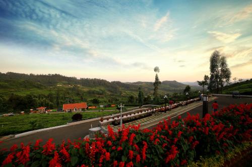 een rij treinwagons op een weg met rode bloemen bij Western Valley Resorts in Ooty