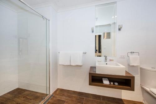 La salle de bains blanche est pourvue d'un lavabo et d'une douche. dans l'établissement Perry Street Hotel, à Mudgee