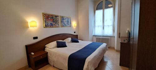 een slaapkamer met een groot bed met blauwe kussens erop bij Hotel Bonazzi in Perugia