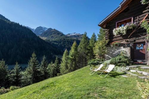 un paio di sedie sedute sul lato di una casa di "CHALET dei FIORI" room & apartment a Bedretto