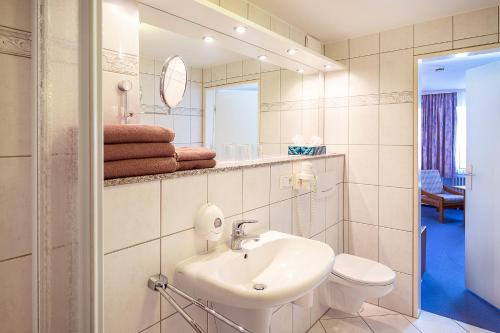 a bathroom with a sink and a toilet and a mirror at Hotel Am Steinberg in Hildesheim