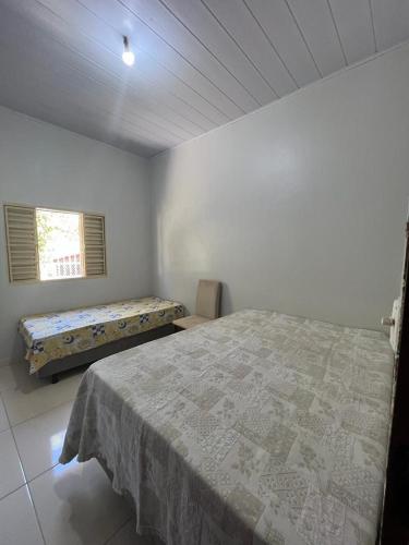 Habitación blanca con cama y ventana en CASA DE FÉRIAS en Barra do Garças