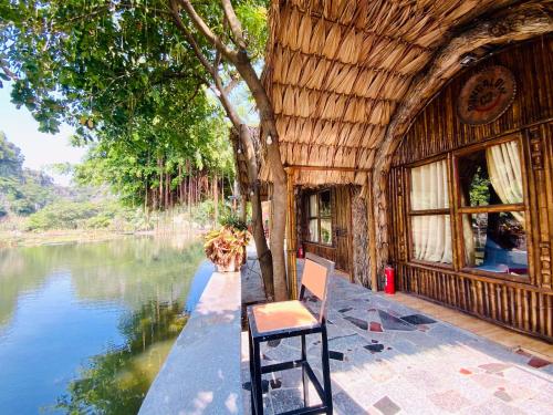 una silla sentada al lado de una casa junto al agua en Tam Coc Bungalow en Ninh Binh