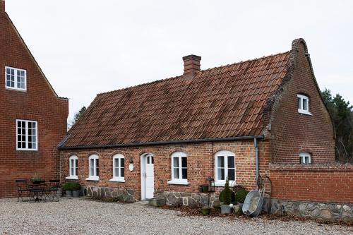 une maison en briques avec des fenêtres blanches et un toit dans l'établissement Gartnerhuset på Kollerup, à Hadsten Stationsby