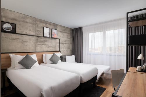 2 łóżka w pokoju hotelowym z biurkiem i stołem w obiekcie ibis London Earls Court w Londynie