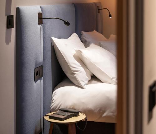 1 dormitorio con cama con almohadas blancas y mesa en Hébé Hotel en Annecy