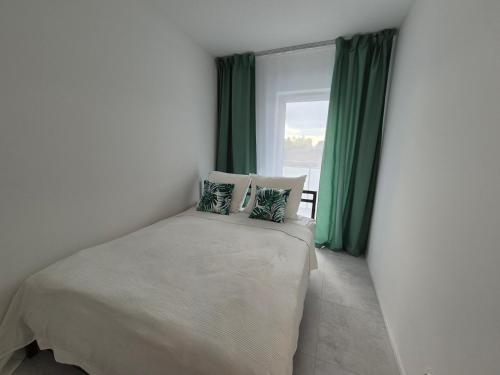 um quarto com uma cama com cortinas verdes e uma janela em Apartament Zacisze 4 em Piaseczno