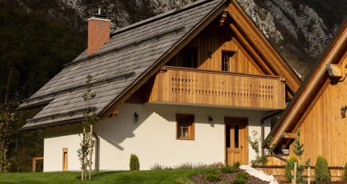 uma casa com um telhado de madeira e uma varanda em PRIVILLAGE Stare - B&B em Bohinj