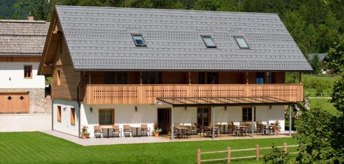 uma grande casa com um telhado de madeira com mesas e cadeiras em PRIVILLAGE Stare - B&B em Bohinj