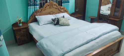 una camera da letto con un grande letto con lenzuola e cuscini bianchi di Zuned Homes Sylhet a Sylhet