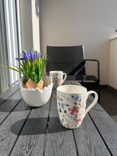 una mesa con dos tazas y un jarrón con flores en Stan na Dan Vrbas Zeljko, en Vrbas