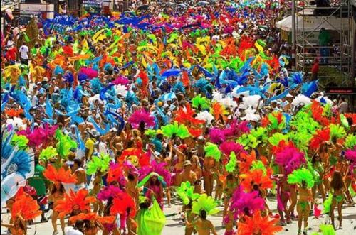 una gran multitud de personas vestidas con disfraces coloridos en The Zen Den en Puerto España