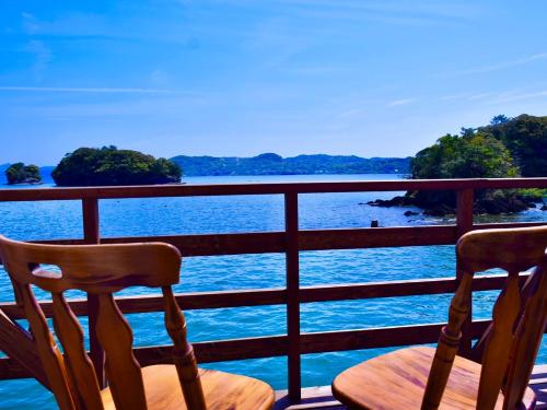 - deux chaises assises sur un balcon donnant sur l'eau dans l'établissement ホワイトハウス, à Sasebo