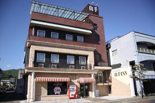 a building with a red phone booth in front of it at ビジネスホテル 山手INN in Iidamachi