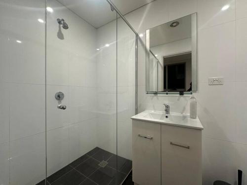 ein weißes Bad mit einem Waschbecken und einer Dusche in der Unterkunft Cozy & Spacious 3 Bedroom House Glebe in Sydney