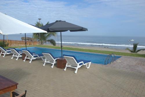 un grupo de sillas y sombrillas junto a una piscina en Hotel Gran Azul Bungalows en Canoas de Punta Sal