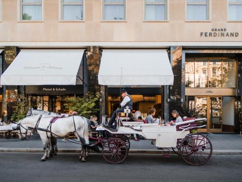 un hombre montando un carruaje tirado por caballos en una calle de la ciudad en Grand Ferdinand Vienna – Your Hotel In The City Center, en Viena