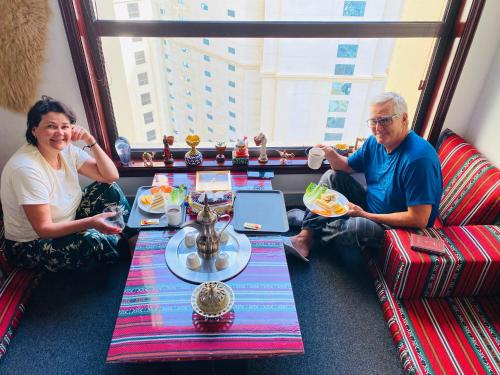 un homme et une femme assis à une table mangeant de la nourriture dans l'établissement Dreams beach hostel, à Dubaï