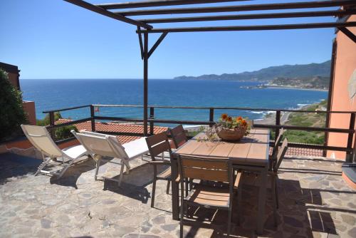 una mesa y sillas en un patio con vistas al océano en DOMO A MARE en Magomadas