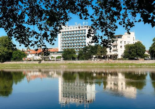 un reflet d'un bâtiment dans une masse d'eau dans l'établissement Hotel Magnólia, à Piešťany