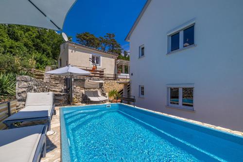 una piscina frente a una casa con sombrilla en Guest House Stella, en Dramalj