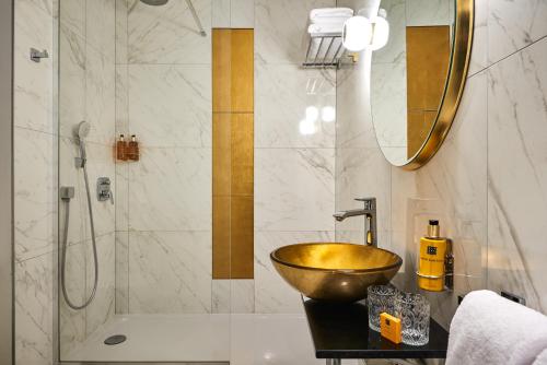 y baño con lavabo de oro y ducha. en Hôtel Le Versailles en Versalles