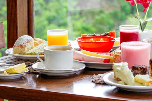 una mesa con platos de comida y una taza de café en VELINN Hotel Ninho do Falcão, en Monte Verde